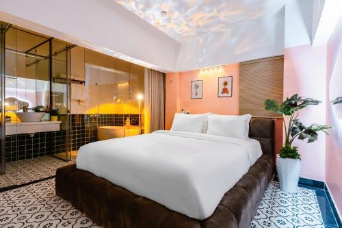 a large white bed in a room with a bathroom at Cosy Hotel in Ho Chi Minh City