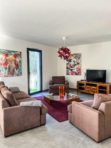 un salon avec deux canapés et une télévision dans l'établissement L'olivette de Sommières, belle maison calme à quelques minutes du centre ville historique, à Sommières