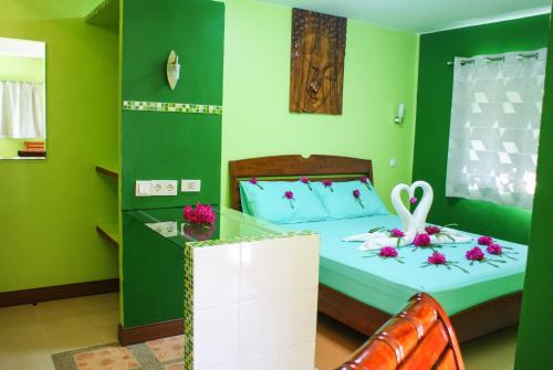 um quarto verde com uma cama com flores em Rock Inn Bailan em Ko Chang