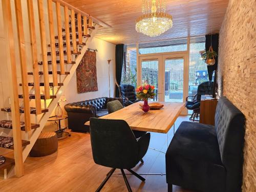 a living room with a table and chairs and a staircase at Ferienhaus am Fuße der Dünen! BG05 in Biggekerke