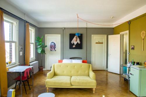 a living room with a yellow couch and a table at Cafe Modern in Amsterdam