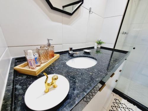 a bathroom with two sinks and a black counter at Flat em Muro Alto - Porto de Galinhas - MAKIA B117 - By Anfitrião Legal in Porto De Galinhas
