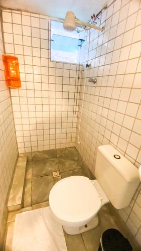 a bathroom with a toilet and a tiled wall at Hospedagem do Marcão in Belo Horizonte