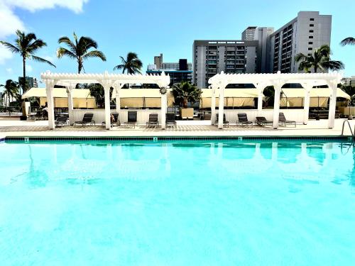 a large swimming pool with white gazebos and palm trees at Ocean Canal Mountain View Steps from Waikiki Beach 6person in Honolulu