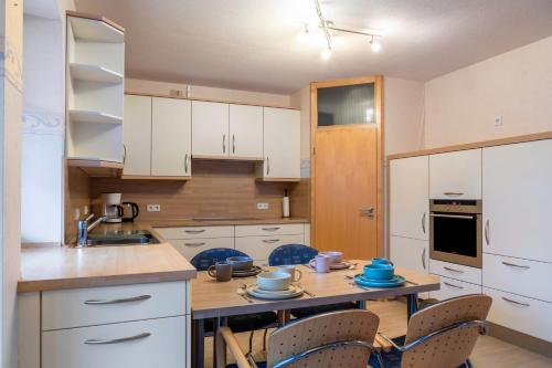 a kitchen with white cabinets and a table with chairs at Ferienwohnung 1 Hof Schäfer in Waldeck