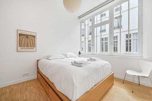 une chambre blanche avec un grand lit et une chaise dans l'établissement 145 sq meter Loft with AC, à Paris