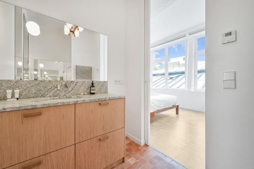 une salle de bain avec un lavabo et un grand miroir dans l'établissement 145 sq meter Loft with AC, à Paris