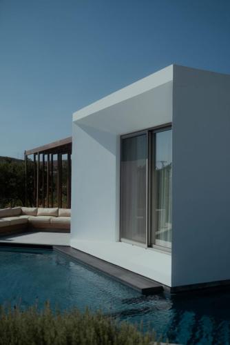 a house with a swimming pool in front of it at PNOĒS Tinos in Tinos