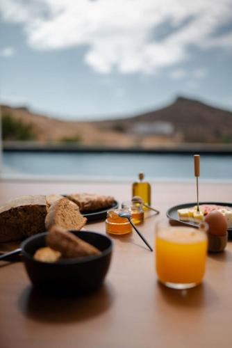 een tafel met borden vol eten en sinaasappelsap bij PNOĒS Tinos in Tinos Town