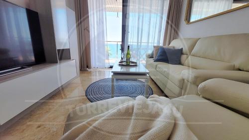 a living room with a couch and a tv at Torrevieja4u Front Sea View Apartment in Torrevieja