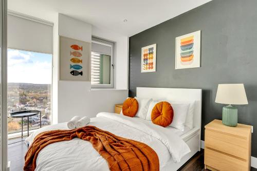 a bedroom with a bed with orange pillows and a window at Last-Minute Escape l Sleeps Up to 6 l Stylish City Views Near Station by Capital Retreat Short lets & Serviced Accommodations in Merton