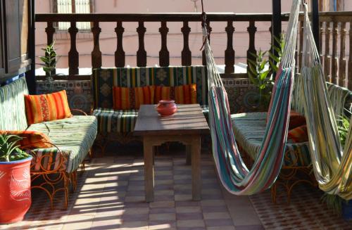 a porch with a hammock and a table and chairs at Sunset Surfhouse Morocco in Tamraght Ouzdar