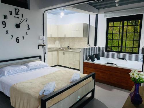 a bedroom with a bed and a bath tub and a clock at Hotel Curazao Natural Living in Cocorná