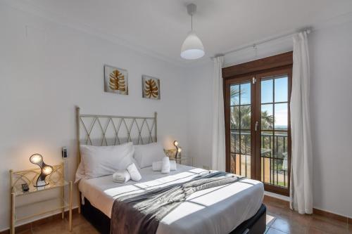 ein Schlafzimmer mit großem Bett und Fenster in der Unterkunft Las Palmeras by Ĥ - Playa Punta del Moral PLHP9P14 in Punta del moral
