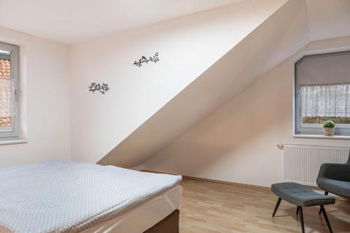 a white bedroom with a bed and a chair at Ferienwohnung 2 Hof Schäfer in Waldeck