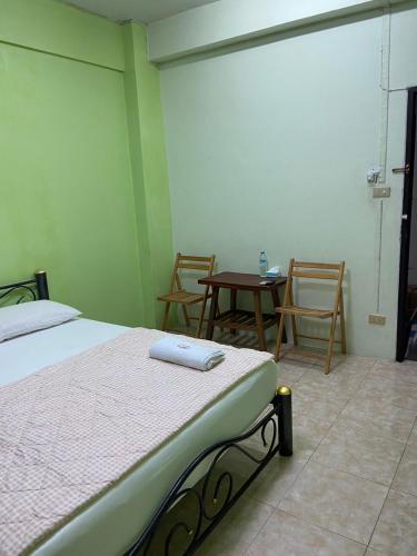 a bedroom with a bed and two chairs and a table at PTT Mansion ปทิตา แมนชั่น in Ban Zong Katiam