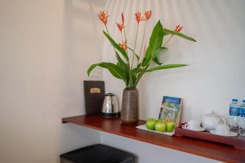 a plant in a vase sitting on a wooden shelf at Phuoc Dat Riverside Homestay Hoi An in Hoi An