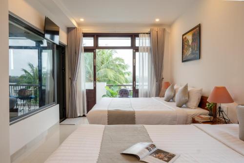 a hotel room with two beds and a balcony at Phuoc Dat Riverside Homestay Hoi An in Hoi An