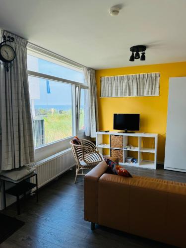 a living room with a couch and a large window at Beachhouse Seepaertje - Boulevard Noordwijk aan Zee in Noordwijk aan Zee