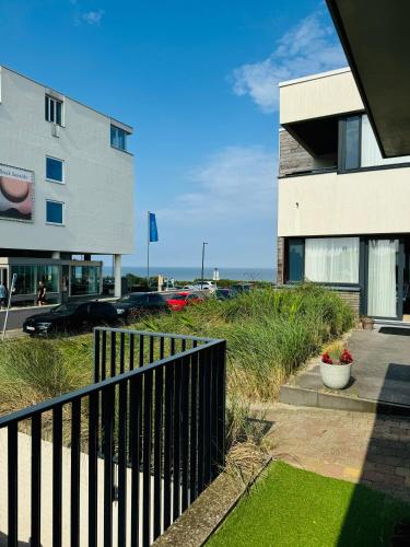 a view of a building with a fence and grass at Beachhouse Seepaertje - Boulevard Noordwijk aan Zee in Noordwijk aan Zee