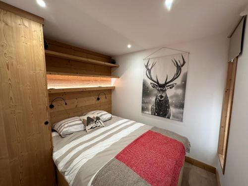 - une chambre dotée d'un lit avec une photo de cerf sur le mur dans l'établissement Appartement rénové cosy avec belle vue, à Montgenèvre