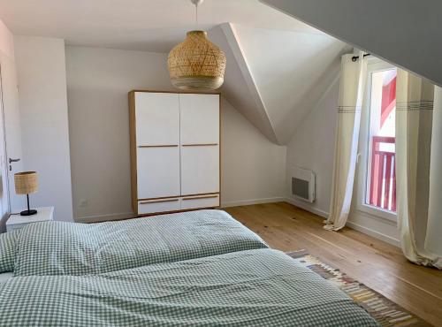 a bedroom with a bed and a large window at Appartement à 200m de la plage in Lacanau