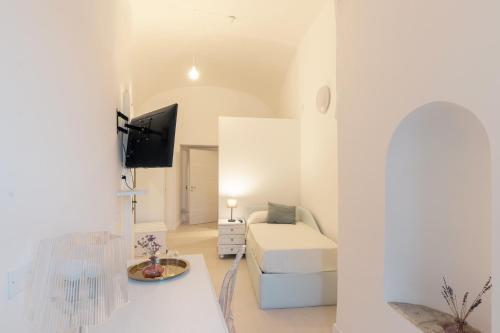 a white room with a bed and a tv at Dimora Margherita in Caserta