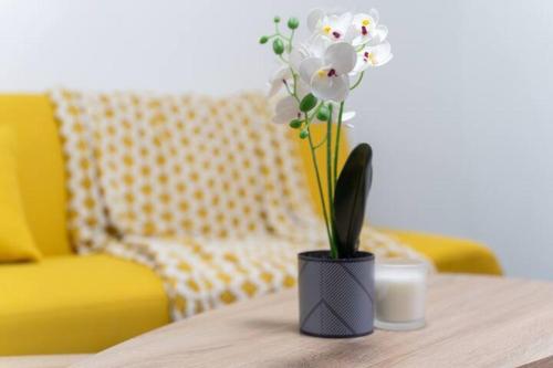 a vase with white flowers on a table with a yellow chair at Open Mind Property - Luxury House & Free Parking in Portsmouth