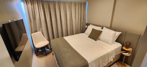 a small bedroom with a bed and a chair at Parque do Cais - Flats Premium no Recife por Yolo in Recife