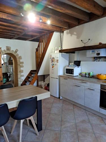 une cuisine avec une table et un réfrigérateur dans l'établissement La Maison de Tigery, à Tigery