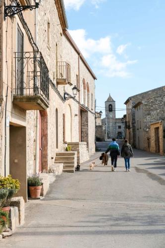 two people and a dog walking down a street at Casa Comalats in Ametlla