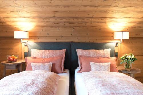two beds in a room with wooden walls at Lech Lodge - LEGENDARY in Lech am Arlberg