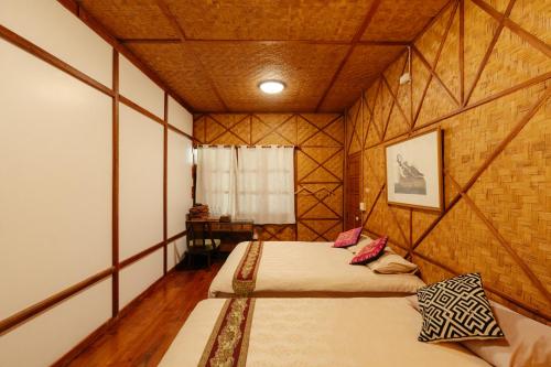 a bedroom with two beds in a room with wooden walls at Ashi Guesthouse Chiangdao in Chiang Dao