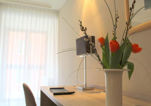 a table with a vase with orange flowers in it at Hotel Erzgiesserei Europe in Munich