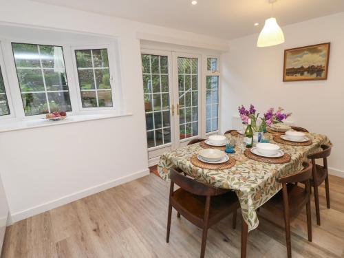 a dining room with a table and chairs and windows at High Tide in Cowes