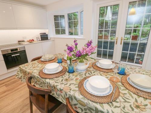 a kitchen with a table with plates and flowers on it at High Tide in Cowes