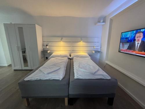 two beds in a room with a tv on the wall at Benjamin Apartman in Budapest