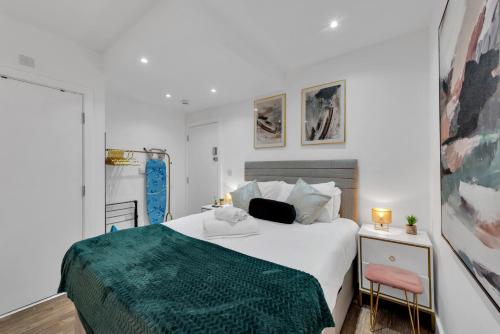 a bedroom with a white bed with a green blanket at Micro Chic, Tiny Studio with Functional Desk in Hanwell