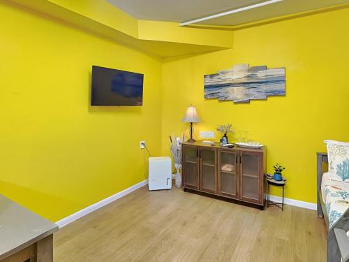 sala de estar con pared amarilla y TV en Seawall Celebration - Manor, en Galveston