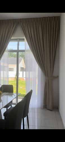 a dining room with a table and chairs and a large window at Homestay Mdm Mai 2 in Masjid Tanah