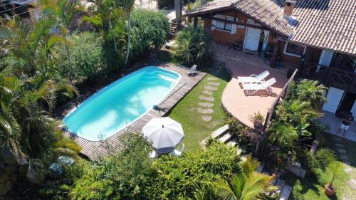 einen Blick über einen Pool mit Sonnenschirm in der Unterkunft Pousada VistaCalma in Praia do Rosa