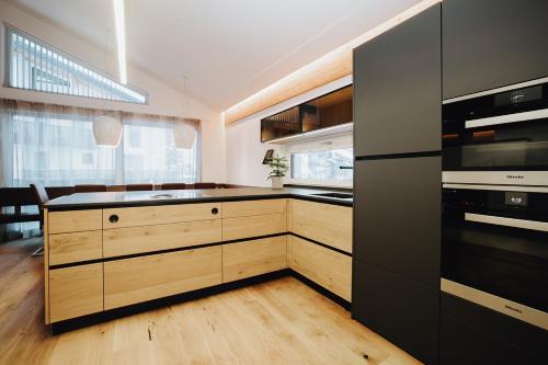 a kitchen with black appliances and wooden cabinets at Knappensteig Appartements in Wagrain