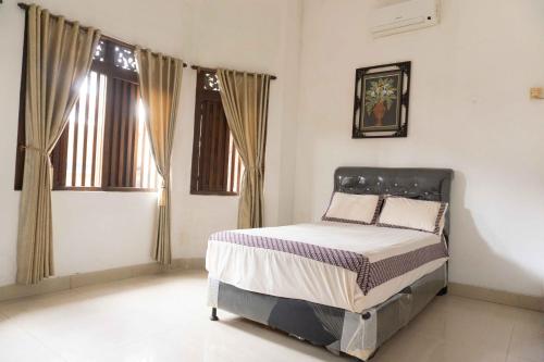 a bedroom with a bed and two windows at Jati Lawas Homestay Jogja by Anvia in Ngabean