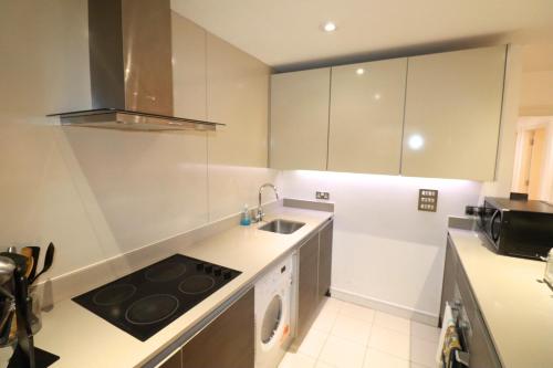 a kitchen with a stove top oven next to a sink at MAIDENHEAD Stylish and modern 2 bedroom apartment in Maidenhead