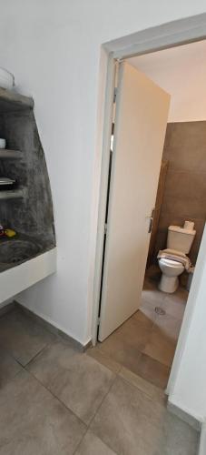 a bathroom with a toilet and a door open at Joannes Vacation Rooms in Adamas