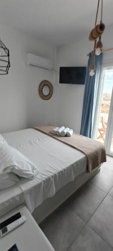 a white bedroom with a bed with a window at Joannes Vacation Rooms in Adamas
