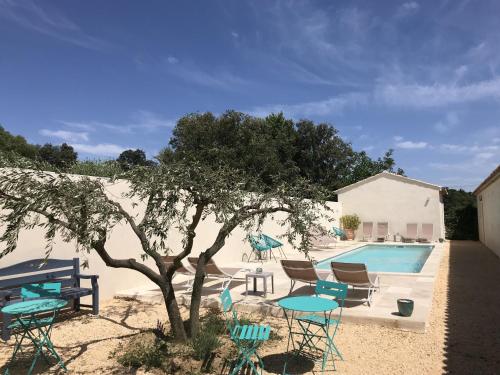 une piscine avec des chaises, une table et un arbre dans l'établissement Les Mazets et Spa D'Uzes, à Arpaillargues-et-Aureillac