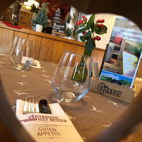 a table with two wine glasses on top of it at Der Tröpolacherhof Hotel & Restaurant in Tröpolach