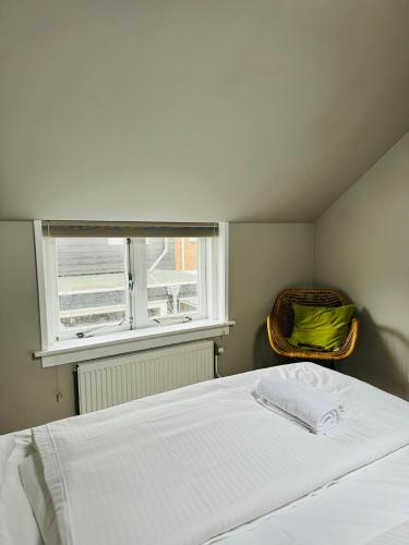 a bedroom with a white bed and a window at Hello Katwijk - Zomerhuis Paul Krügerstraat 3 in Katwijk aan Zee