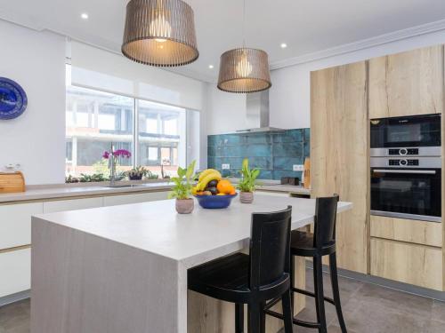 une cuisine avec une grande île blanche et des chaises noires dans l'établissement Casa Anzano, à Santander